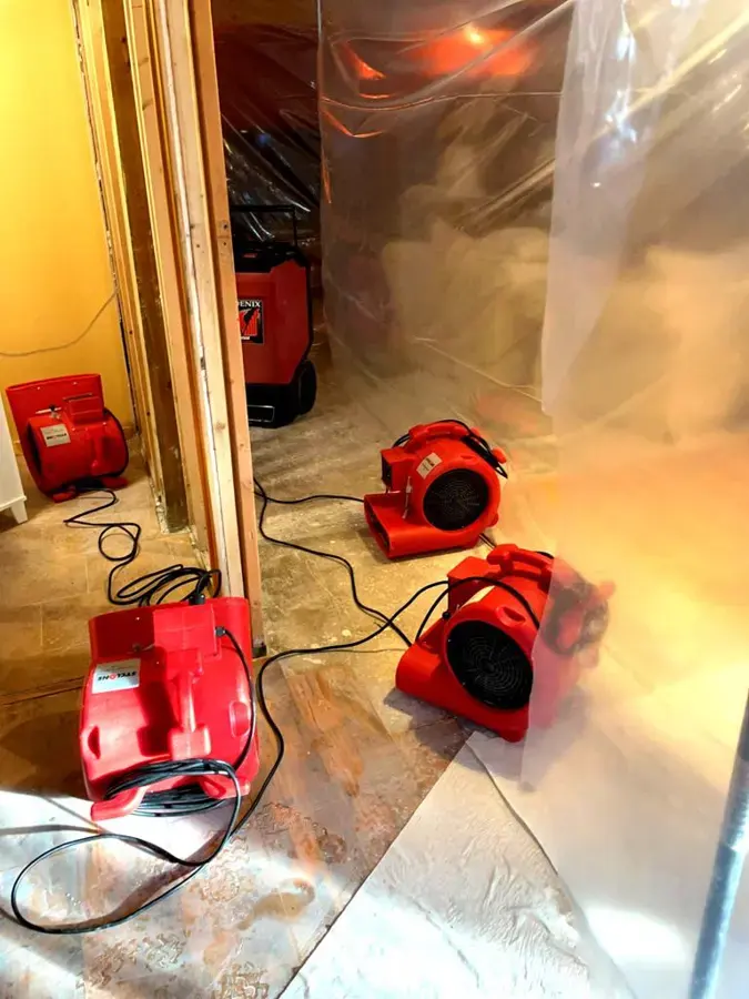 Air movers and a dehumidifier drying a room in an Eagan house during a water loss