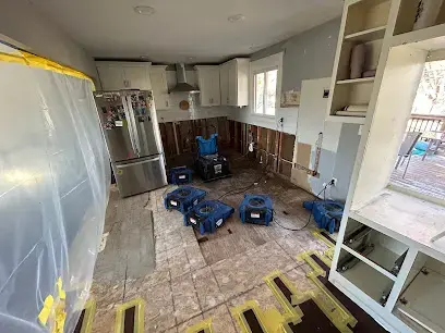 Kitchen under containment plastic with air movers drying the subfloor
