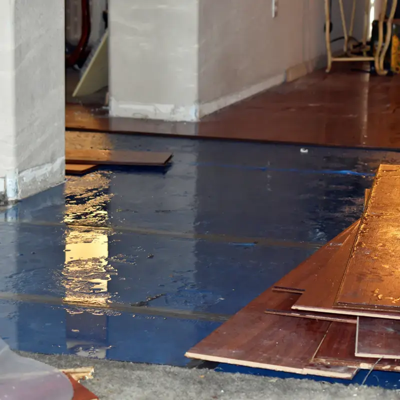 Standing water over a subfloor with wet wood flooring planks pulled up